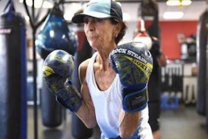 A senior woman with boxing gloves participates in boxing therapy for Parkinson’s Disease