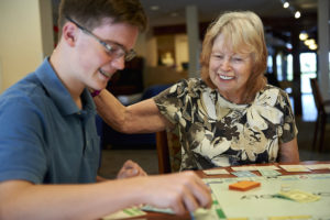 A grandson plays a board game with his grandparents while on vacation together