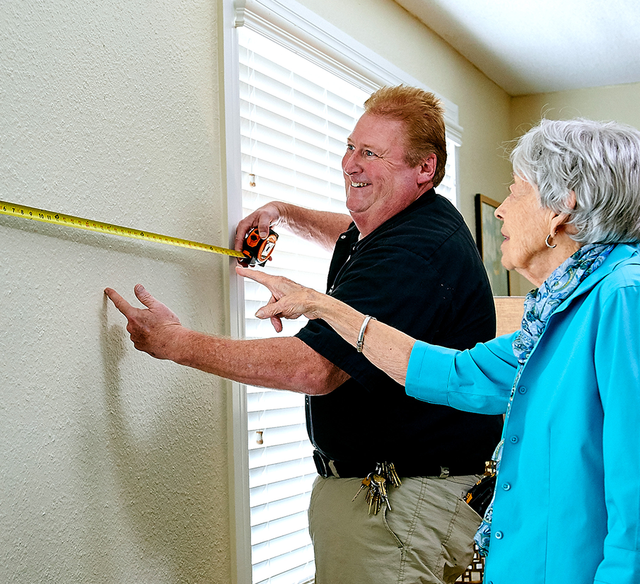 Man helping senior with hanging items on a wall