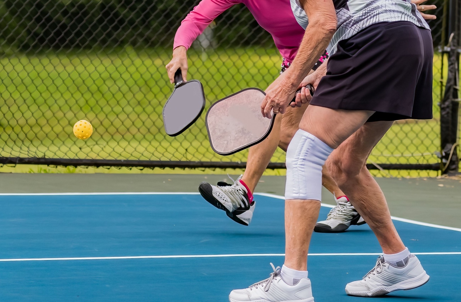 Two senior friends enjoy a game of pickleball on an outdoor court