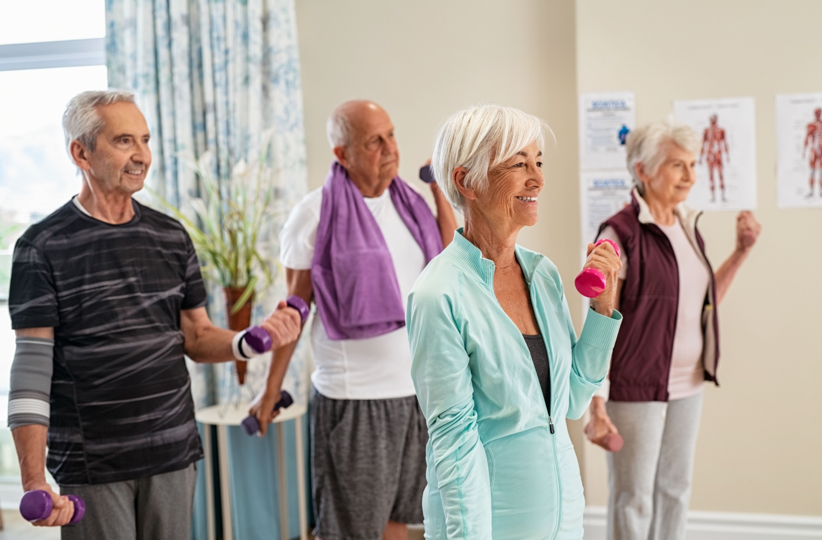 A group of senior residents use light dumbbells to do a light exercise routine together, helping to strengthen their balance over time.
