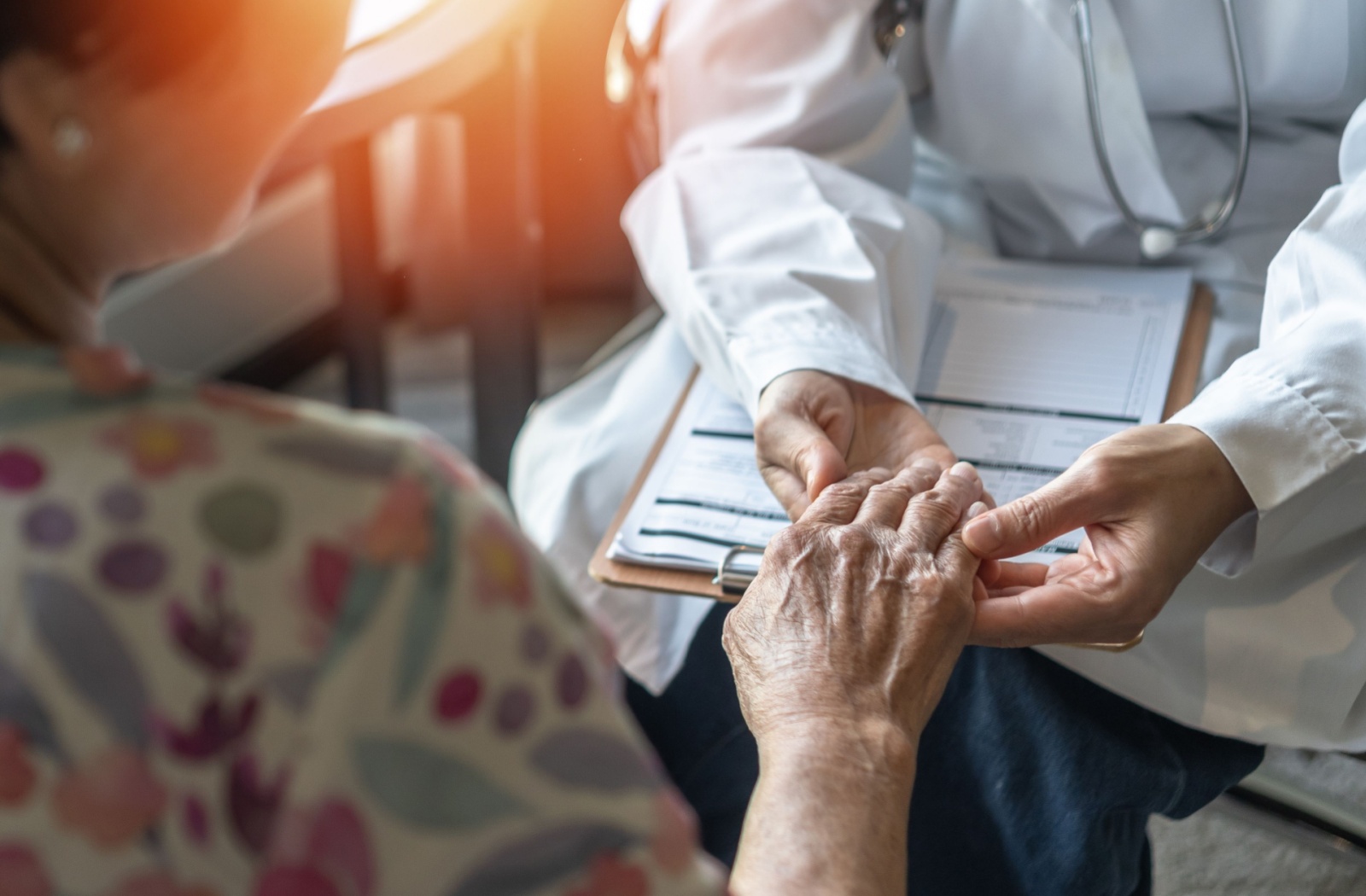 A medical professional holds the hand of a senior living with dementia.
