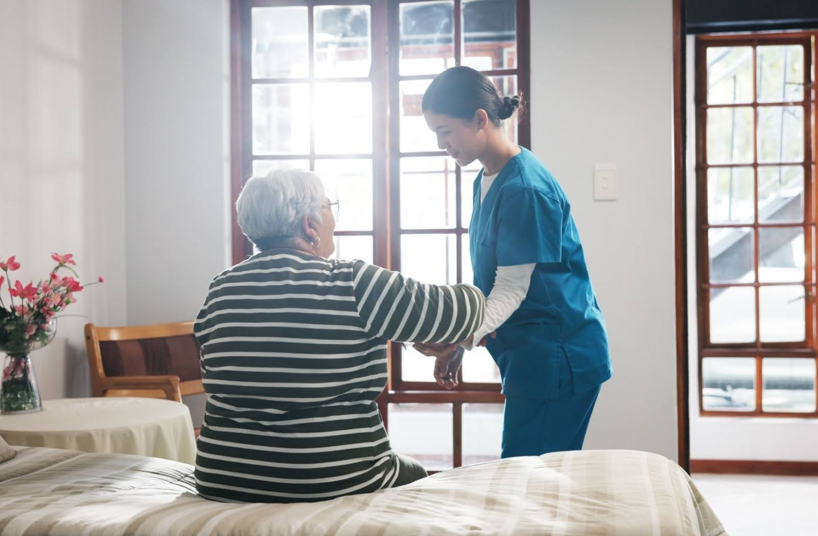 A senior living caregiver assists a resident out of bed.