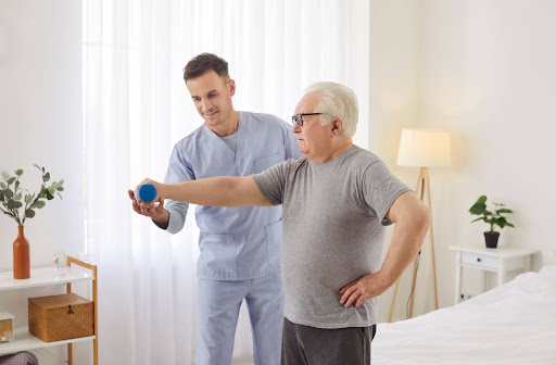 A senior living caregiver assists a resident with some light arm exercises