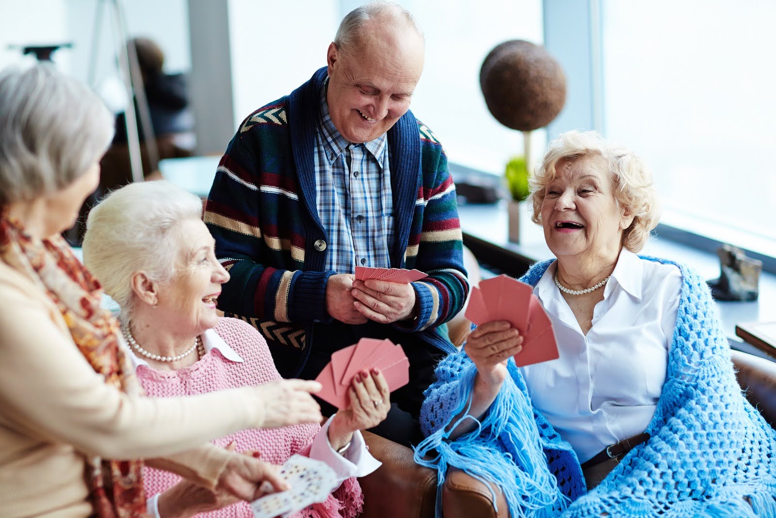 Group of happy seniors playing cards together and smiling hard at each other.