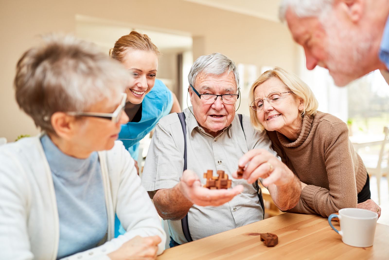 A group of seniors in a retirement home plays with a wooden puzzle as a therapy