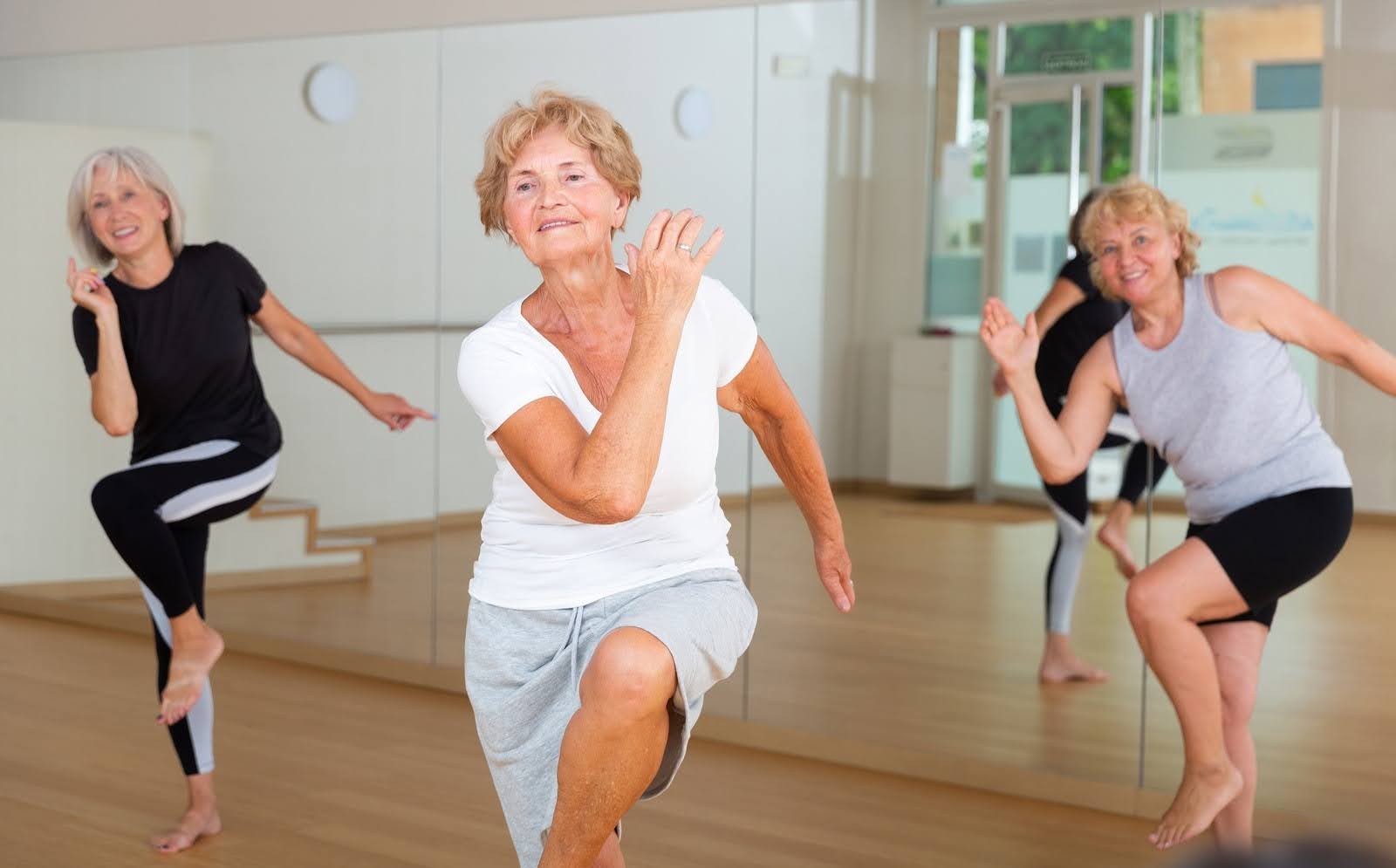 Active elderly lady leading a choreography class with a group of elderly women, learning modern dynamic dances and staying together